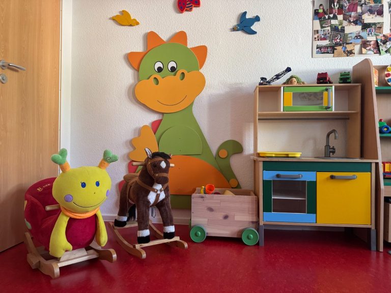 Spielzimmer, Spielzeug Bunte Spielzeuge in einem Kinderzimmer mit einem Drachen-Wandbild und einer Spielküche.